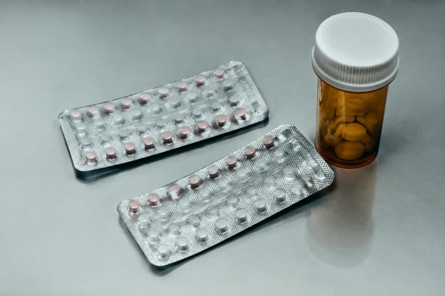 Contraceptive pill packets and a prescription bottle on a clinical surface